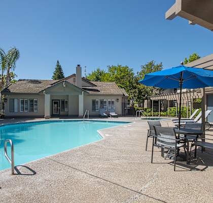 A pool with chairs and umbrellas at Zinfandel Village Apartments, California, 95670