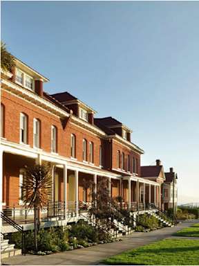 A row of red brick buildings with white trim and a clear blue sky.