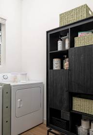 A black shelf with a basket on top and a white cabinet below it.