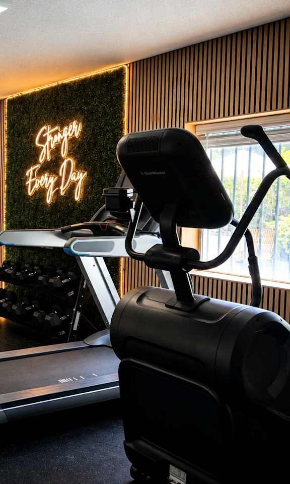 A home gym with a treadmill, weights, and exercise equipment.