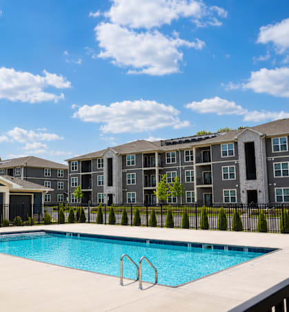 A swimming pool in front of a building with a black fence.