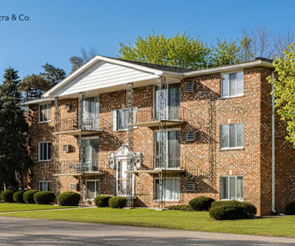 A brick apartment building with a white picket fence in front.