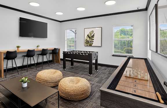 A room with a shuffleboard table and a television.