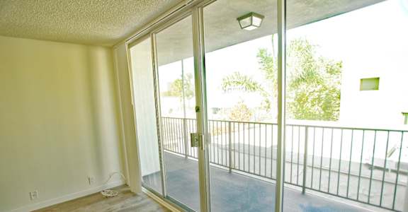 A room with a sliding glass door leading to a balcony.