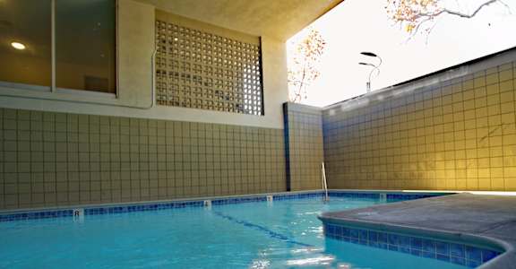 A swimming pool with blue water and a tiled wall.