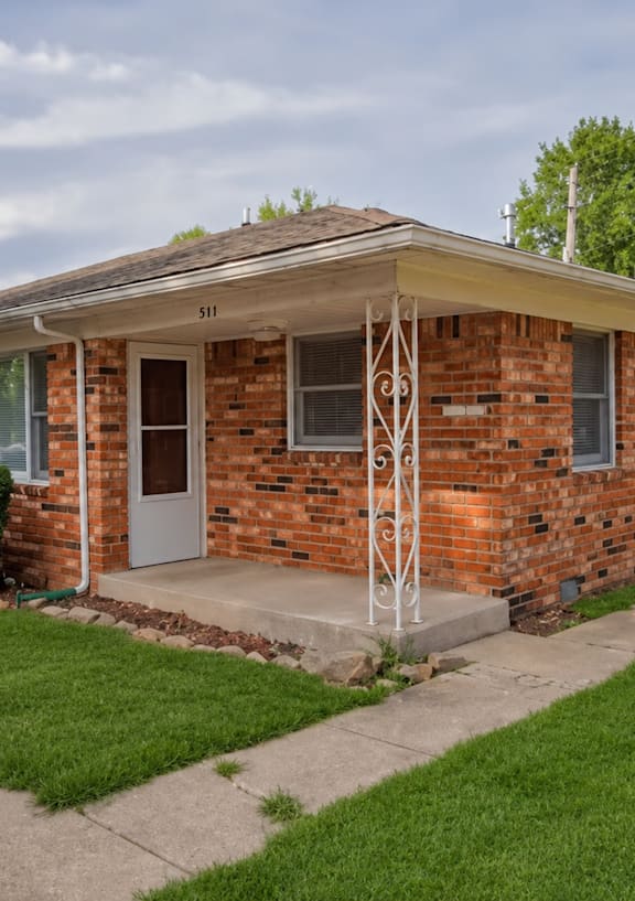 A brick house with a white window and a door.