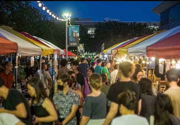 A busy night market with people walking and shopping.