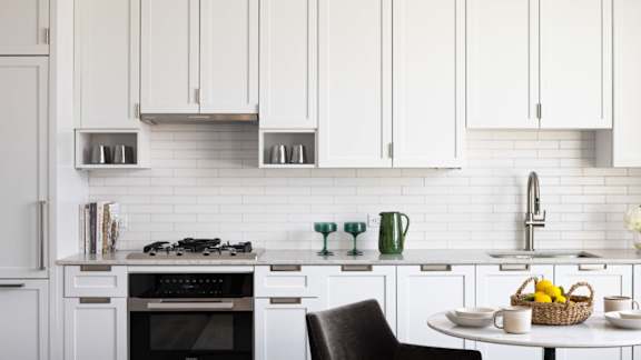 A kitchen with white cabinets and a black chair.