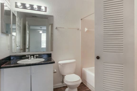 Bathroom with Black Counters White Cabinets and Sliding Closet Doors