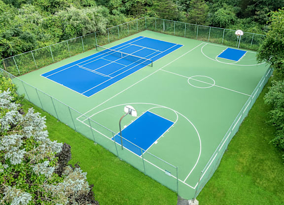A tennis court surrounded by a fence and trees.