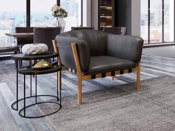 A living room with a grey couch, a purple ottoman, and a small table with a plant on it.