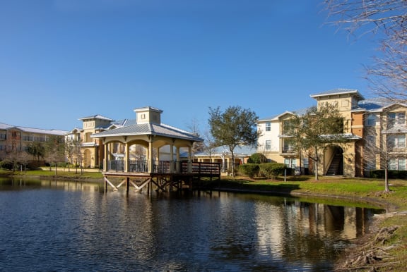 a gazebo in the middle of a pond with apartments in the background