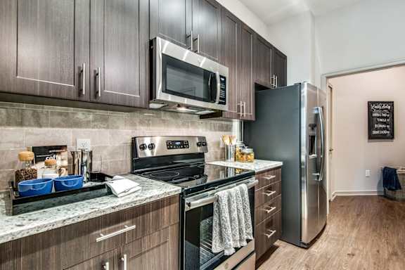 A kitchen with a refrigerator, oven, and microwave.