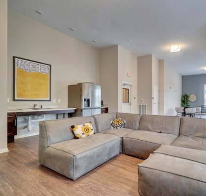 a large couch in a living room with a kitchen in the background