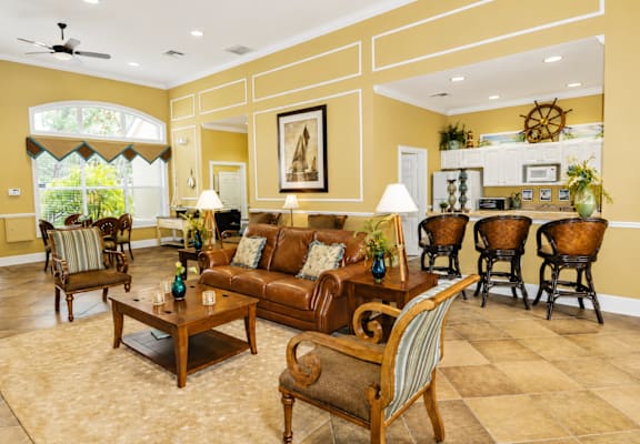 A living room with a brown couch and a painting on the wall.