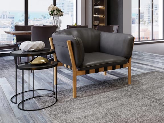 A living room with a grey couch, a purple ottoman, and a small table with a plant on it.
