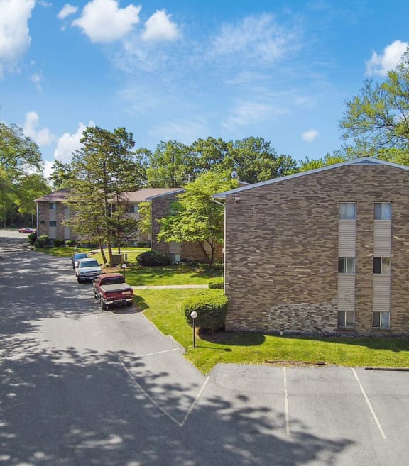 a view from the street of a brick building with two windows and a parking lot in front