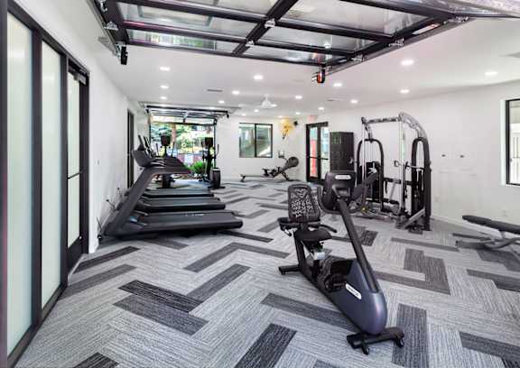 a workout room with treadmills and other exercise equipment