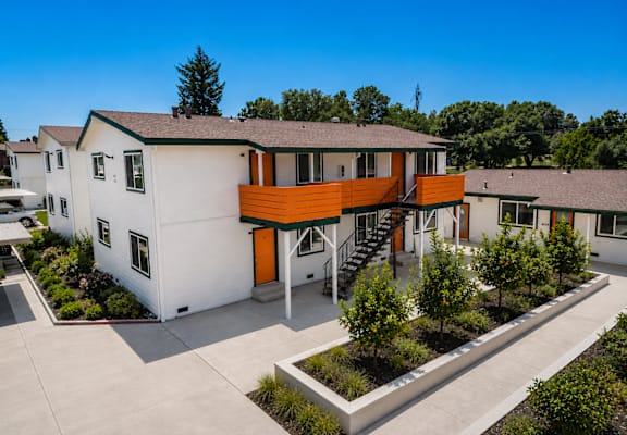 A modern house with a white exterior and an orange accent wall.