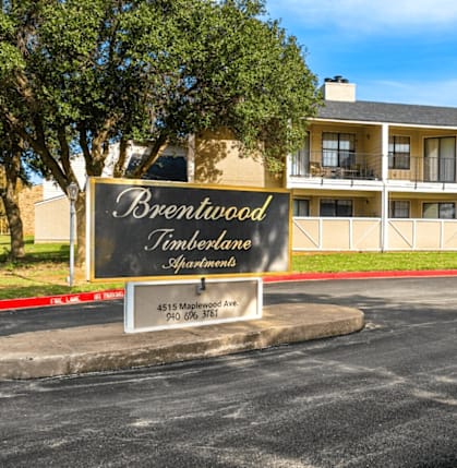 A sign for Brentwood Timberlane Apartments is displayed in front of a building.
