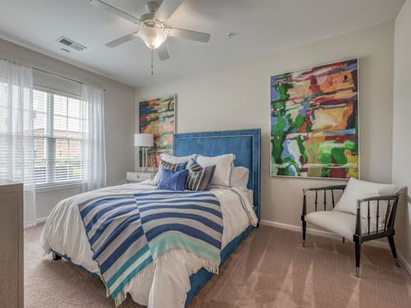 A bedroom with a bed, chair, and painting on the wall.
