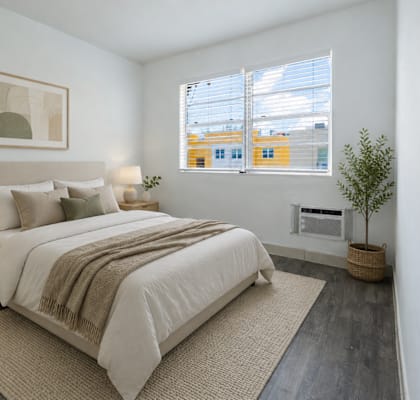 A bedroom with a large bed and a small tree.