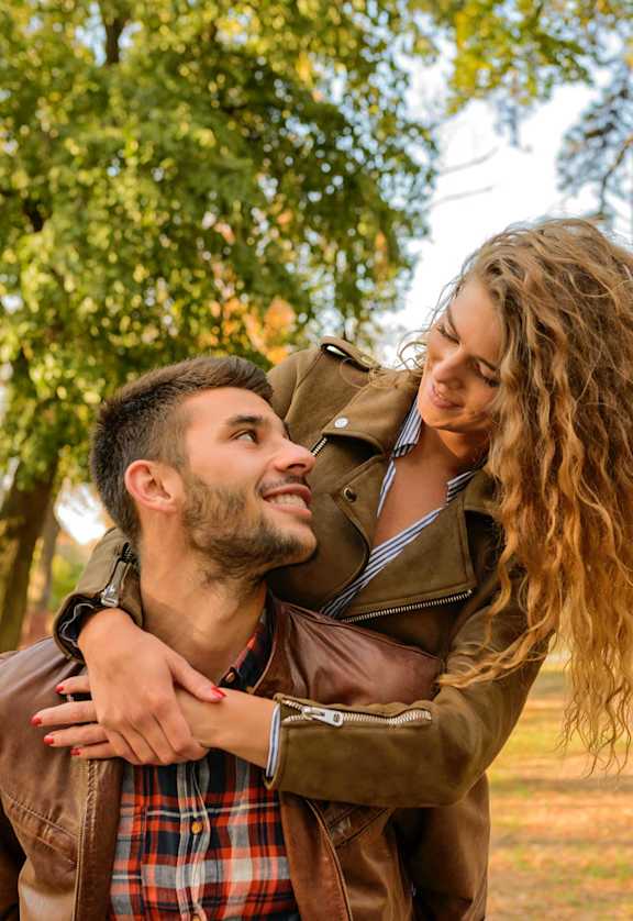 a man and a woman holding each other in a park