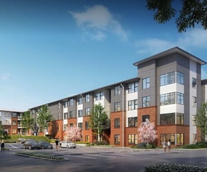 A modern apartment complex with multiple buildings and a parking lot in front.