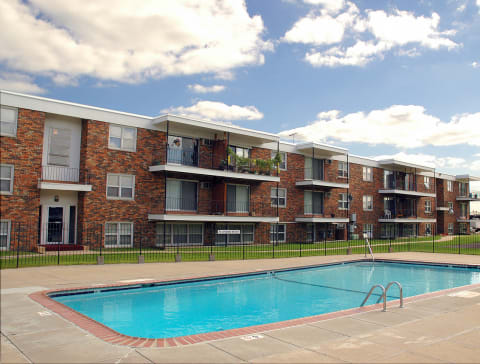 A swimming pool is located in front of apartment buildings at Point of America Apartments,Brooklyn Park