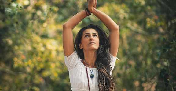 a woman sitting on the ground with her hands up in a yoga pose