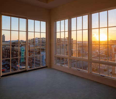an empty living room with windows overlooking a city at sunset at Mercantile on Broadway, Fargo, ND 58102