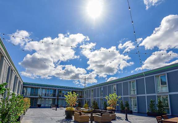 A sunny day at a modern outdoor seating area with a clear blue sky and fluffy white clouds.