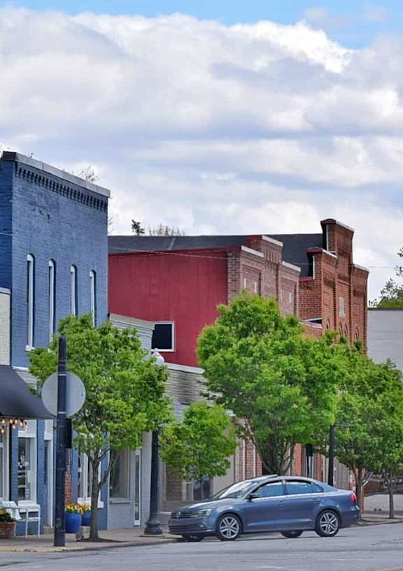 A street view of a town with a blue car parked on the side of the road.