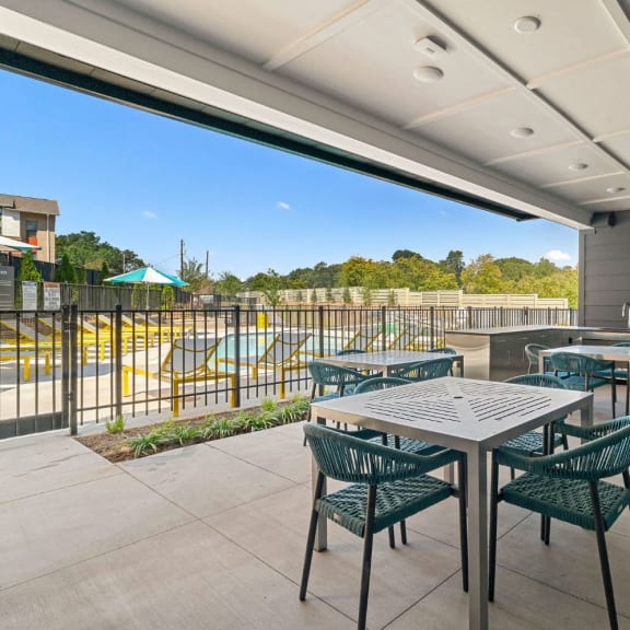 a patio with tables and chairs and a pool in the background