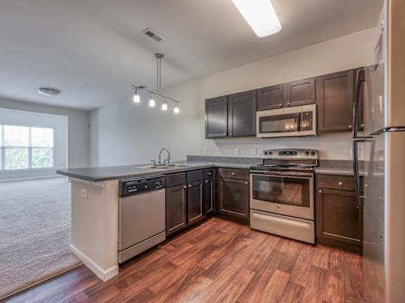 A modern kitchen with stainless steel appliances and wooden floors.