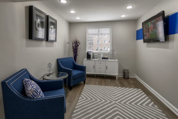 Waiting room with blue upholstered chairs and tv at The Brook At Columbia Apartments, Maryland, 21044