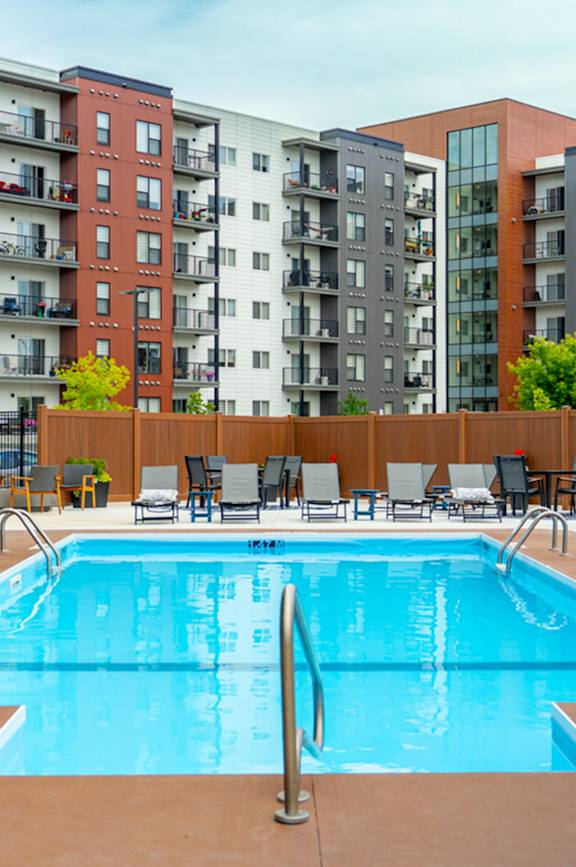 A pool surrounded by chairs and buildings.