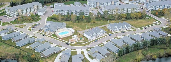 an aerial view of an apartment complex with a pool and a lake