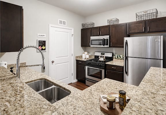 A kitchen with a sink, refrigerator, and microwave.