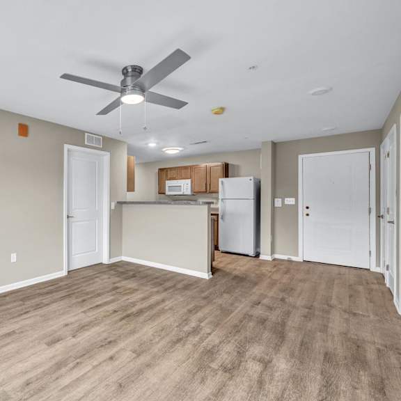 A room with a ceiling fan and a kitchenette.
