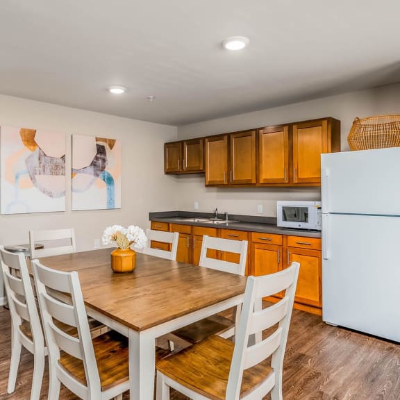 a kitchen with a wooden table and chairs and a white refrigerator
