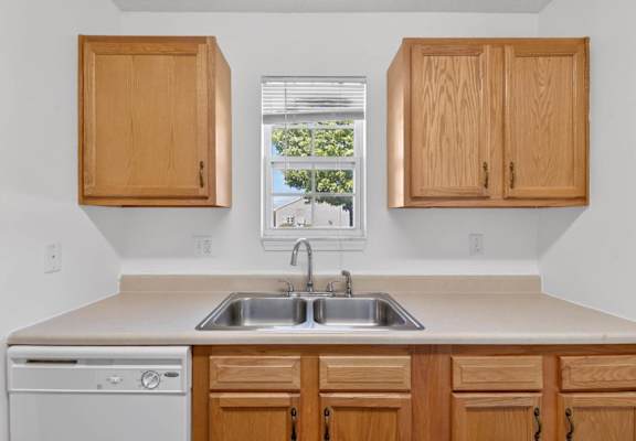 A kitchen with wooden cabinets and a dishwasher.