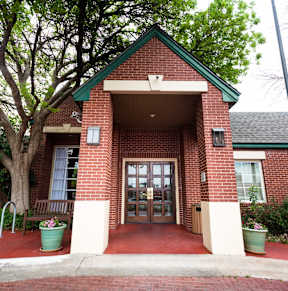 A red brick building with a green roof and a glass door.
