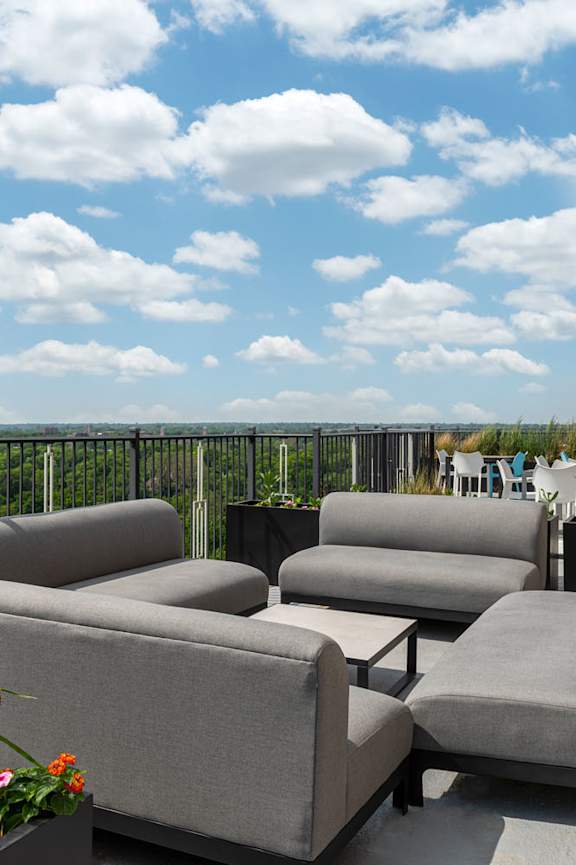 A patio with grey couches and a view of the sky.