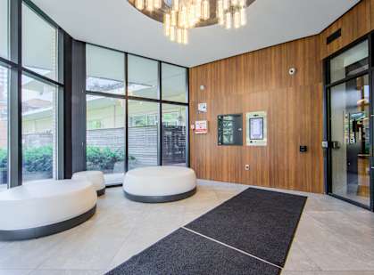 A modern office lobby with a black carpet and a wooden wall.