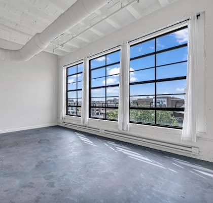 an empty room with large windows and a concrete floor