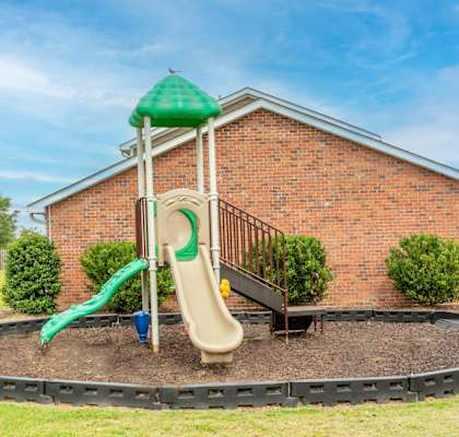 a playground with a slide in front of a brick building