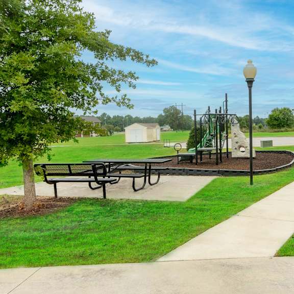 a picnic area with a playground in the background