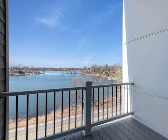 A balcony overlooks a body of water with boats and trees in the distance.