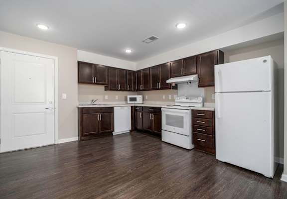 a kitchen with white appliances and dark wood cabinets